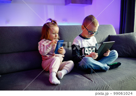 Danya and his sister Emilia play with mobile phones and tablets. 99061024