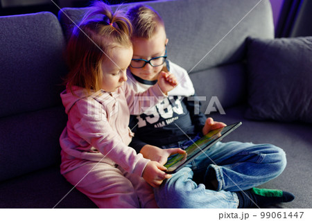 Danya's older brother teaches her younger sister how to use a tablet. 99061447