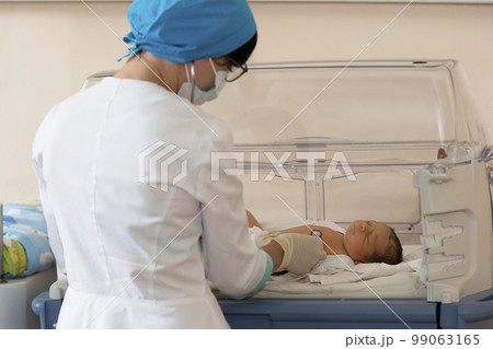 Neonatology. Doctor listening to the heartbeat of a newborn in an infant incubator 99063165