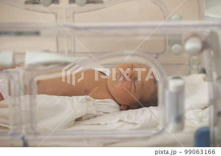 Neonatology. A newborn in a special incubator for babies in a hospital. 99063166