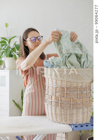 housewife with wicker basket of clean laundry carries ironing, cleaning and washing at home housewife with wicker basket of clean laundry carries ironing, cleaning and washing at home 99064277