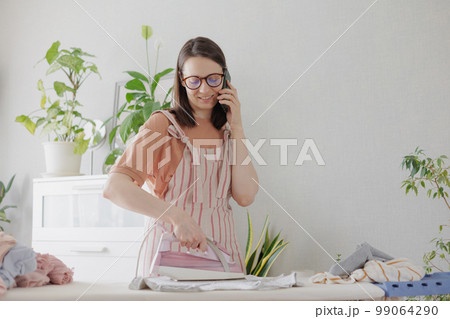 woman irons linen and clothes home, laundry housework textile care. female housewife  99064290
