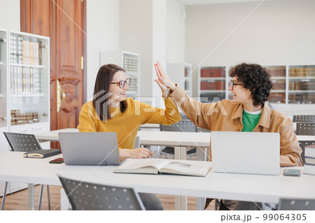 Two female students give high fives and rejoice at victory in creative project 99064305