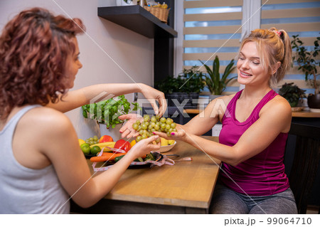 women sitting in the kitchen serving themselves grapes over the table women sitting in the kitchen serving themselves grapes over the table 99064710