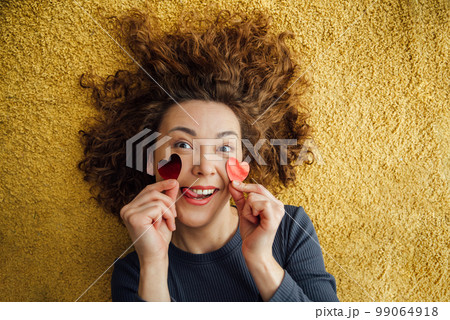 Funny girl sticks her tongue out, flirts with hearts on her cheeks 99064918