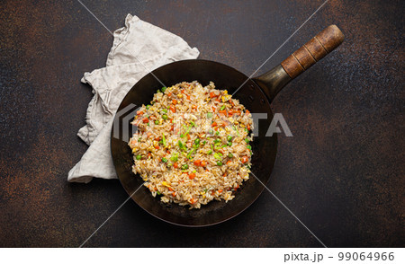 Authentic Chinese and Asian fried rice with egg and vegetables in wok top view, rustic concrete table background. Traditional dish of China 99064966