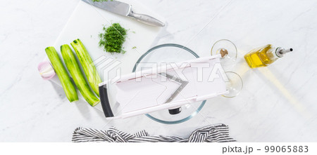 Flat lay. Slicing vegetables on slicer to make summer cucumber salad. Flat lay. Slicing vegetables on slicer to make summer cucumber salad. 99065883