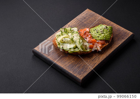 Delicious brown bread toast with salmon, avocado, cucumber and sesame seeds Delicious brown bread toast with salmon, avocado, cucumber and sesame seeds 99066150