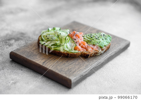 Delicious brown bread toast with salmon, avocado, cucumber and sesame seeds 99066170