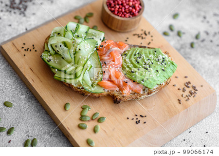 Delicious brown bread toast with salmon, avocado, cucumber and sesame seeds Delicious brown bread toast with salmon, avocado, cucumber and sesame seeds 99066174