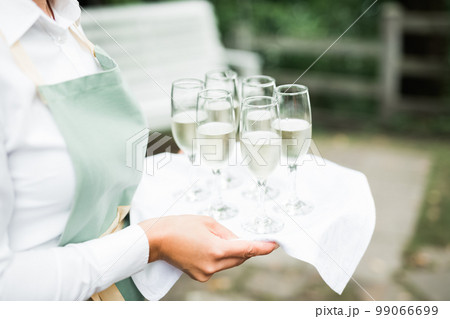 Waiter serving glasses with champagne on a tray Waiter serving glasses with champagne on a tray 99066699