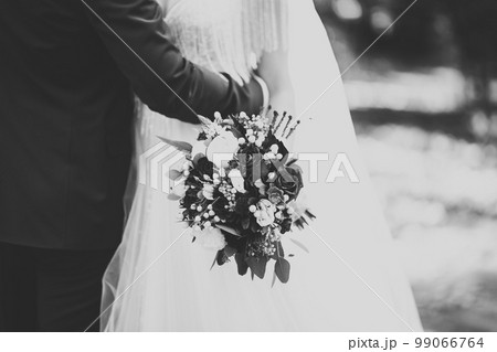 Beautiful young wedding couple posing with bouquet of flowers in hands 99066764