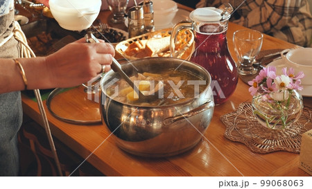 A woman pours hot soup for guests. 99068063