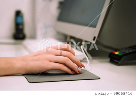 Close up hand of young woman administrator works at the reception of fitness club or health centre Close up hand of young woman administrator works at the reception of fitness club or health centre 99068416