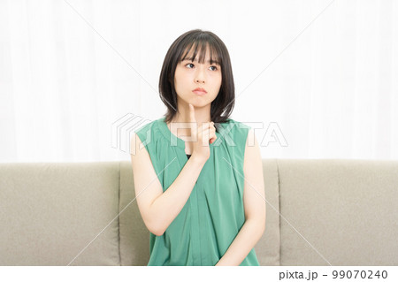 ソファに座って考え事をしている若い女性 99070240