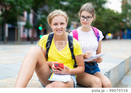 Teen girls teach lessons using smartphones outdoors 99070558