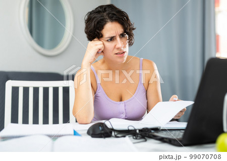 Dissatisfied woman chatting with someone over internet using laptop Dissatisfied woman chatting with someone over internet using laptop 99070708