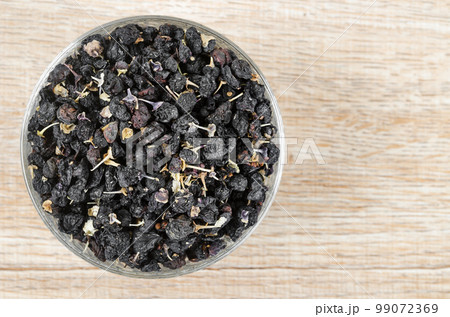The Black wolfberries or black goji berries, in a wooden bowl on table. 99072369