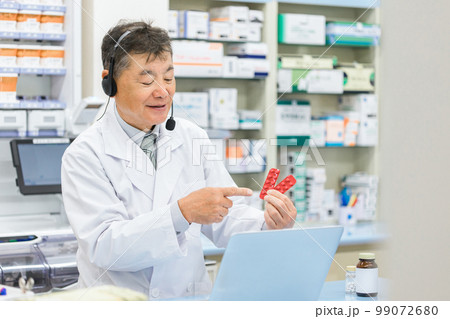 病院・薬局でパソコンを使ってオンライン服薬指導・診療する薬剤師・調剤師の男性（処方箋・医師） 99072680