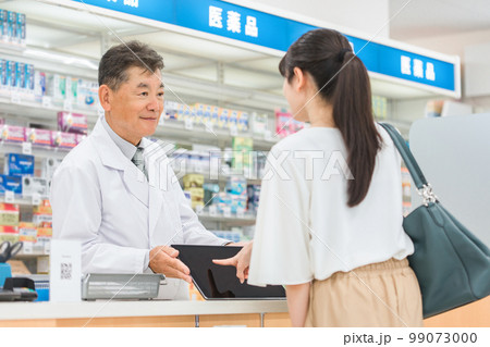 薬局・病院・ドラッグストアでタブレットPCを使って説明する薬剤師（処方箋・薬・サプリメント） 99073000