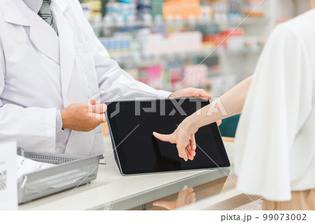 薬局・病院・ドラッグストアでタブレットPCを使って説明する薬剤師（処方箋・薬・サプリメント） 99073002