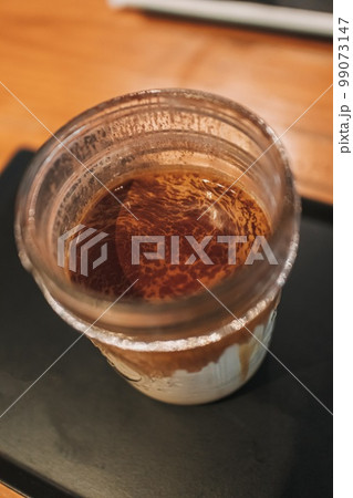 Dirty coffee in transparent glass served on black tray in the cafe. Dirty coffee in transparent glass served on black tray in the cafe. 99073147