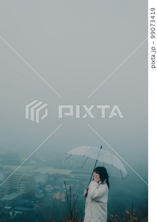 街バックに傘をさしスマホをさわる女性の写真 街バックに傘をさしスマホをさわる女性の写真 99073419