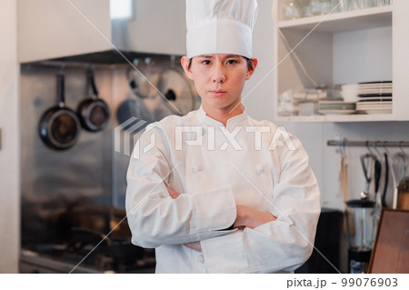 真剣な表情で腕組をする料理人 99076903