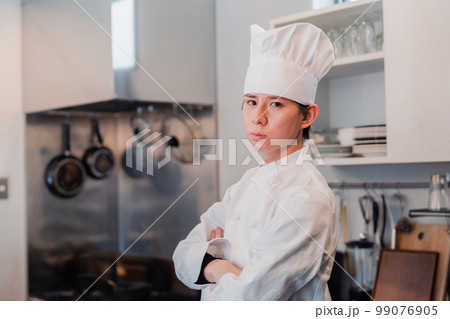 真剣な表情で腕組をする料理人 99076905