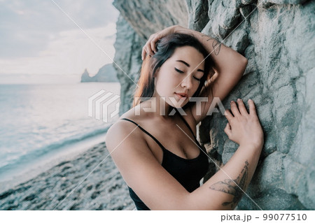 Portrait of cheerful female climber resting on a volcanic basalt Portrait of cheerful female climber resting on a volcanic basalt 99077510
