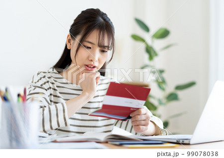 インフレで通帳を見て悩む女性 99078038