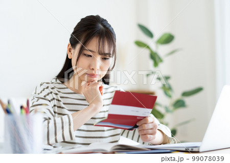インフレで通帳を見て悩む女性 99078039