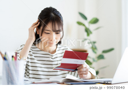 インフレで通帳を見て悩む女性 99078040