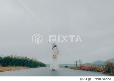 河川敷で傘をさしている女性の写真 99078228