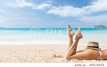 Woman lying on the sea beach 99079009