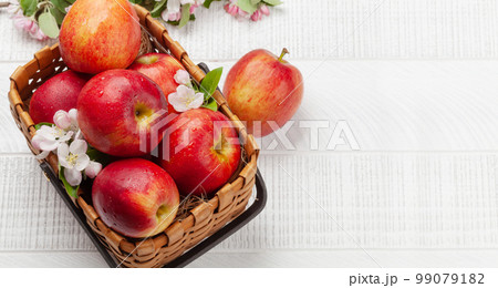 Ripe red apples and apple blossom flowers in basket Ripe red apples and apple blossom flowers in basket 99079182