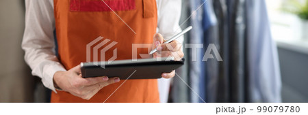 Dry cleaning administrator holds tablet with documents to sign 99079780