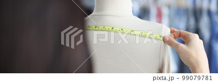 Fashion designer stylist takes measurements with centimeter from clothes on mannequin 99079781