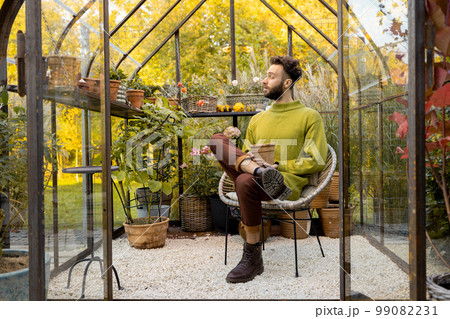Man with flowerpot in greenhouse Man with flowerpot in greenhouse 99082231