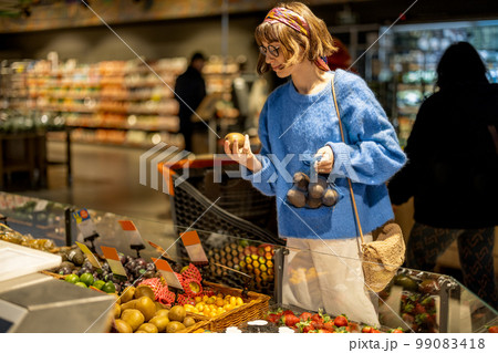 Woman chooses fruits at supermarket 99083418