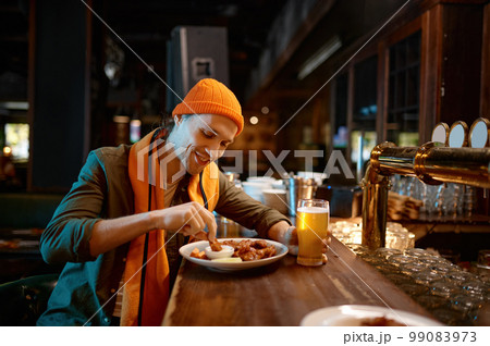 Young man football fan eating snack and drinking beer in sports bar Young man football fan eating snack and drinking beer in sports bar 99083973