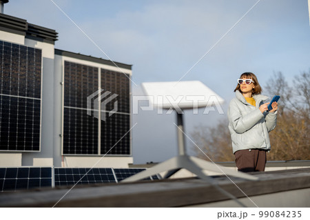 Woman uses satellite internet connection on roof of a house 99084235