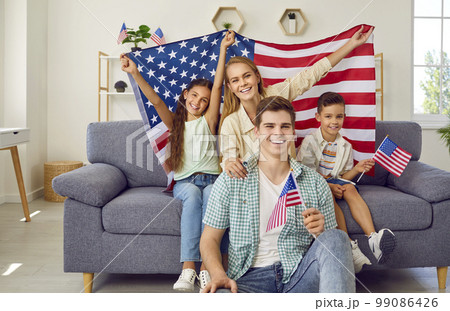 Portrait of happy young American family with children who are holding national flags. 99086426