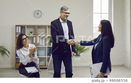Smiling businessman shaking hand of vacancy candidate in office 99086556