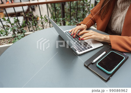 Cropped shot of a woman at cafe working on her laptop computer Cropped shot of a woman at cafe working on her laptop computer 99086962