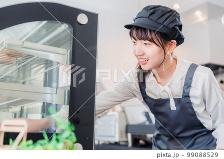 ショーケースに商品を並べる若い店員 99088529