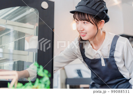 ショーケースに商品を並べる若い店員 ショーケースに商品を並べる若い店員 99088531