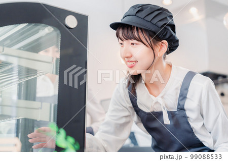 ショーケースに商品を並べる若い店員 99088533