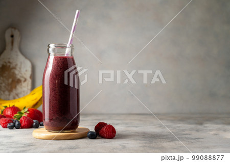 Bottle of berry smoothie in a glass. Strawberry, banana, blueberry healthy drink. Copy space. 99088877