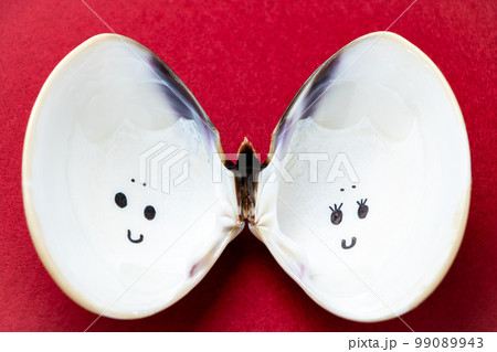 ひな祭りイメージ。夫婦円満の象徴とされるハマグリの貝殻の内部に描かれた、雛人形風の顔。 99089943